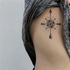 Tatuaje en costado de espalda de mujer con rosa de los vientos y flecha