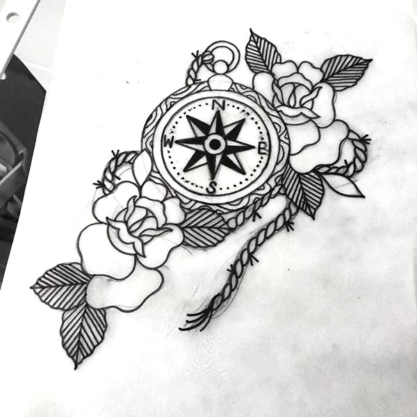 rosas y brújula en un tatuaje con flor de los vientos