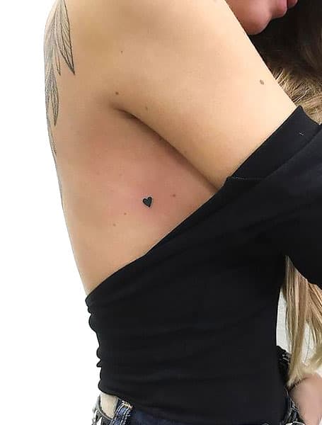 Tatuaje de corazón negro pequeño en la caja torácica de las mujeres