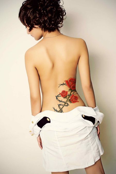 Beautiful red rose branch tattoo on lower back