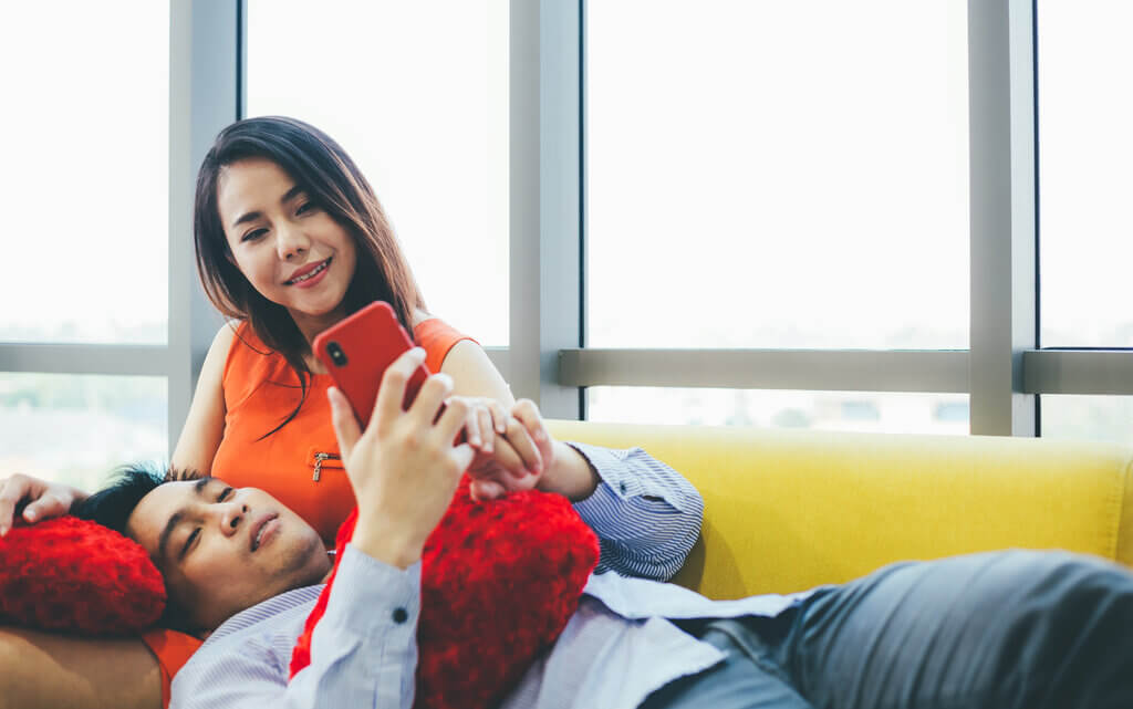 pareja relajándose en casa en el sofá jugando en un dispositivo móvil